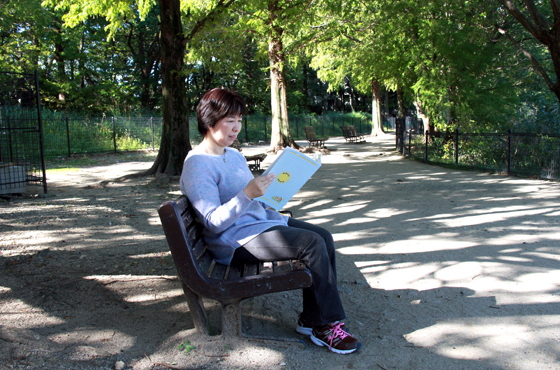 写真：公園のベンチで本を読む竹内さん